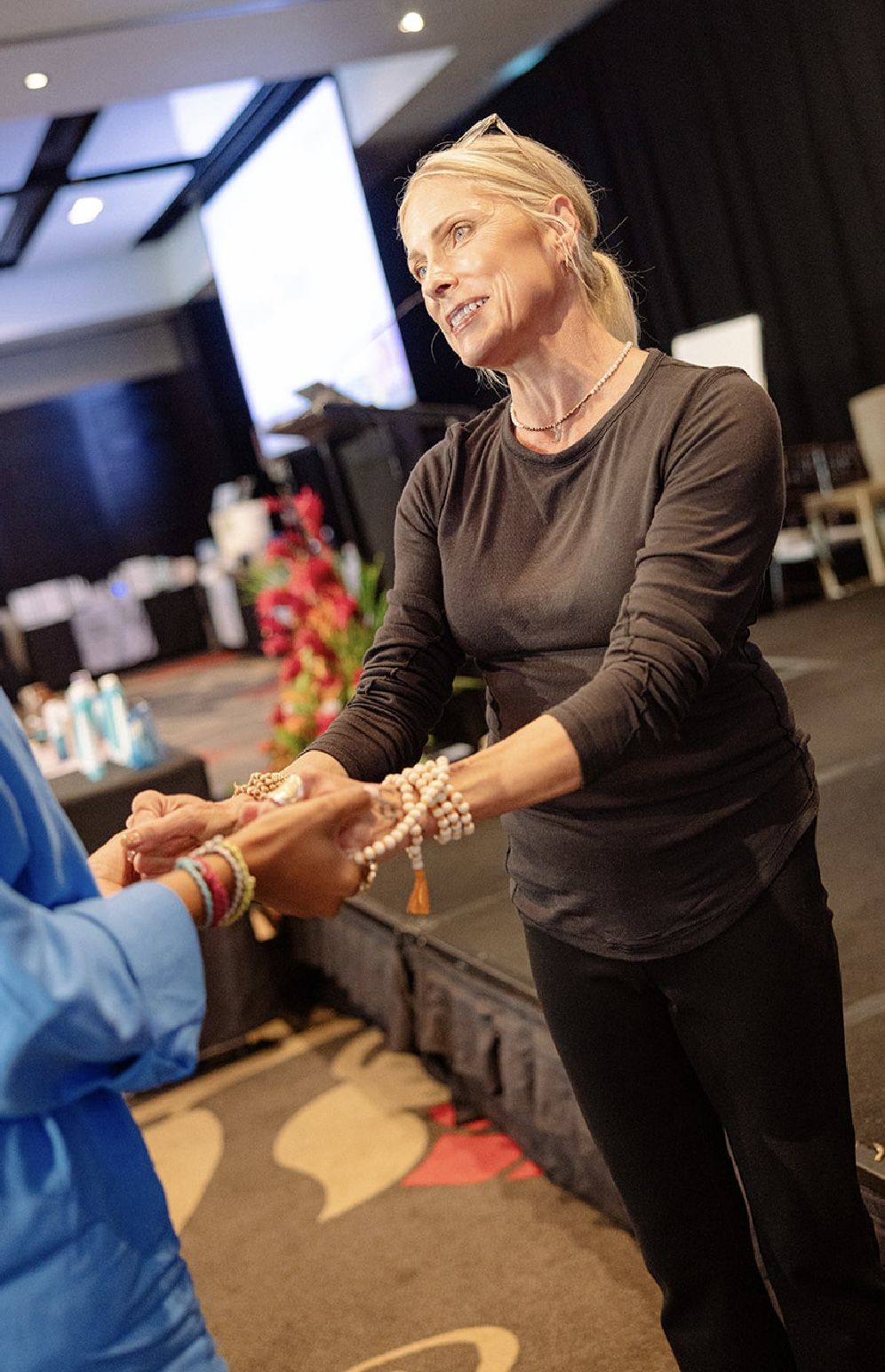 Eva Maurice placing mala beads into a guest's hands at a live event